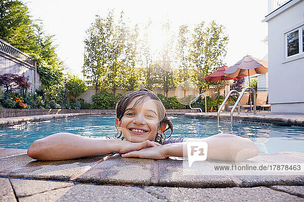 Portrait of smiling boy (10-11) in backyard swimming pool