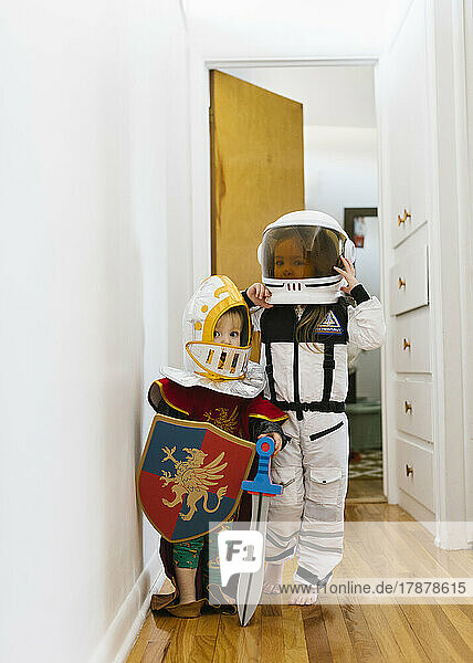 Toddler boy (2-3) in knight costume and girl (2-3) in astronaut costume playing at home