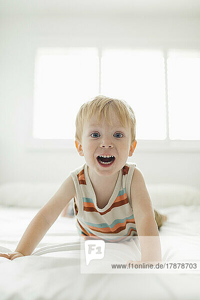 Portrait of smiling boy (2-3) lying on bed