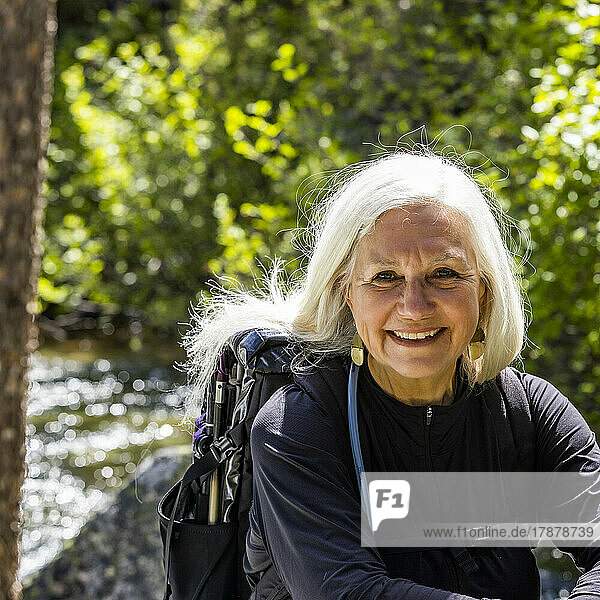 United States  Idaho  Stanley  Senior blonde woman resting by rushing stream near Sun Valley