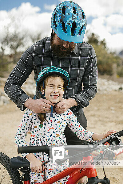 Father adjusting daughters (8-9) bike helmet
