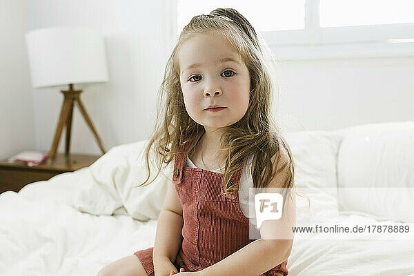 Portrait of girl (2-3) sitting on bed