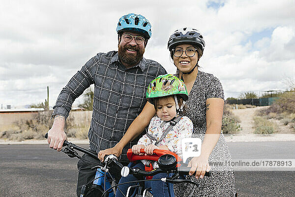 Portrait of family with daughter (2-3) biking together
