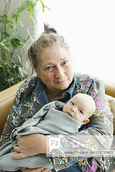 Portrait of smiling grandmother holding newborn grandson (0-1 months)