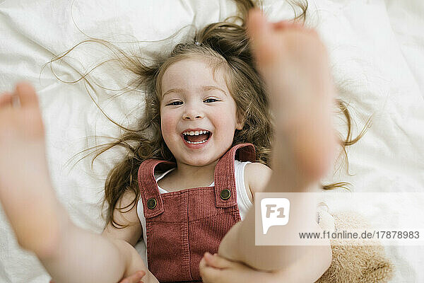 Laughing playful girl (2-3) on bed