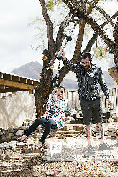 Father swinging daughter (8-9) on swing