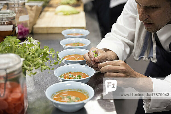 Koch garniert Suppe an der Küchentheke im Restaurant