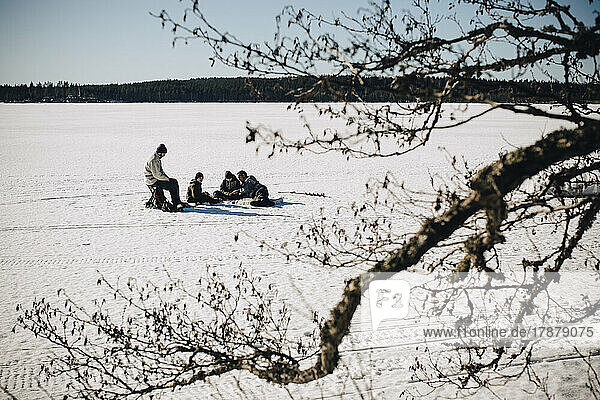 Fathers with sons ice fishing on sunny day in winter