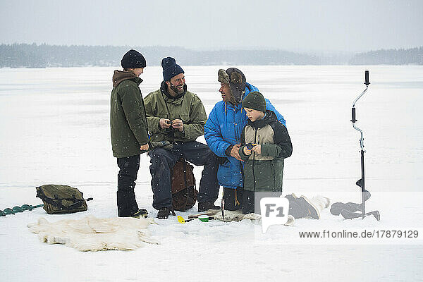 Cheerful male friends enjoying with sons at frozen lake