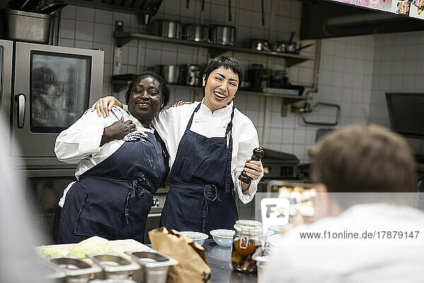 Männlicher Chefkoch fotografiert glückliche Kollegen in einer Großküche