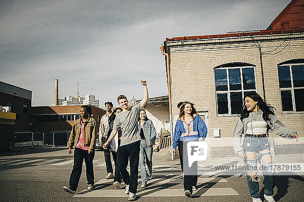 Glückliche multirassische junge Freunde beim Überqueren der Straße in der Stadt