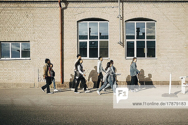Seitenansicht von multirassischen jungen Freunden  die auf einer Stadtstraße spazieren gehen