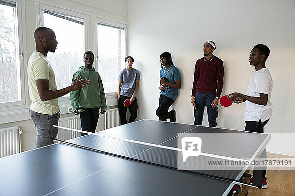 Instructor giving table tennis training to students in games room