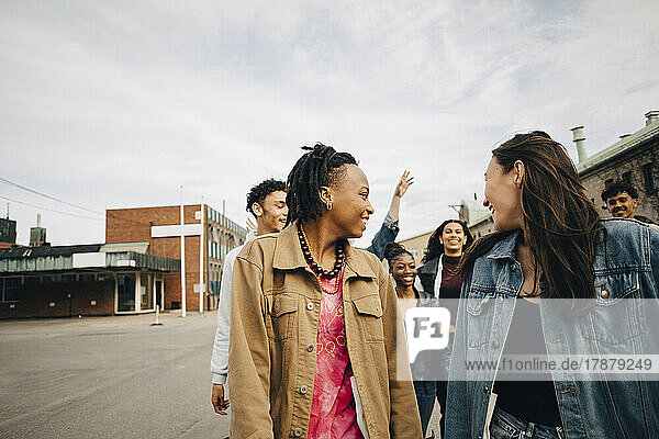 Lächelnde multirassische junge Freunde genießen auf der Straße in der Stadt