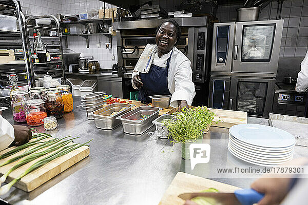 Chefkoch lächelnd bei der Arbeit in der Küche eines Restaurants