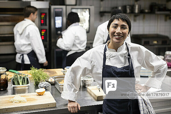 Portrait of smiling female chef standing in commercial kitchen of restaurant