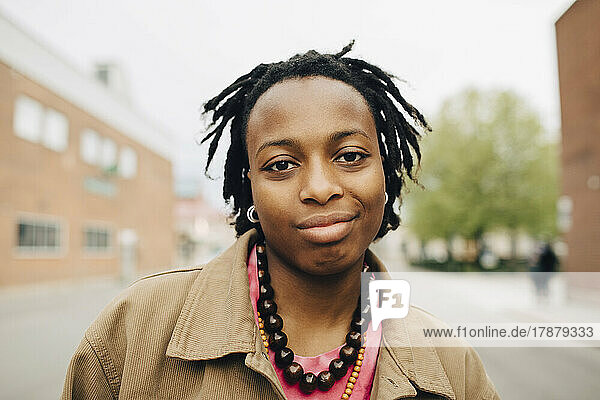 Portrait lächelnde junge Frau mit geflochtenem Haar auf der Straße