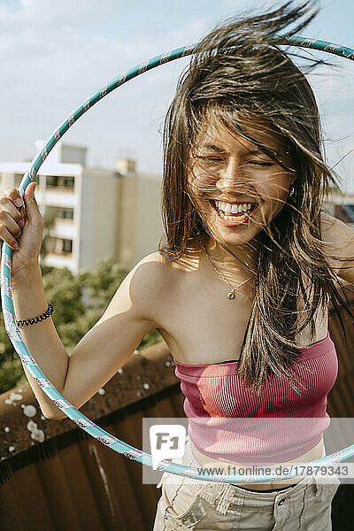 Happy young woman with hoola hoop enjoying on rooftop