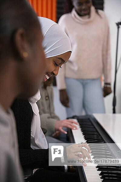 Smiling girl playing piano in recording studio