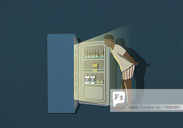 Man standing at open refrigerator in kitchen at night