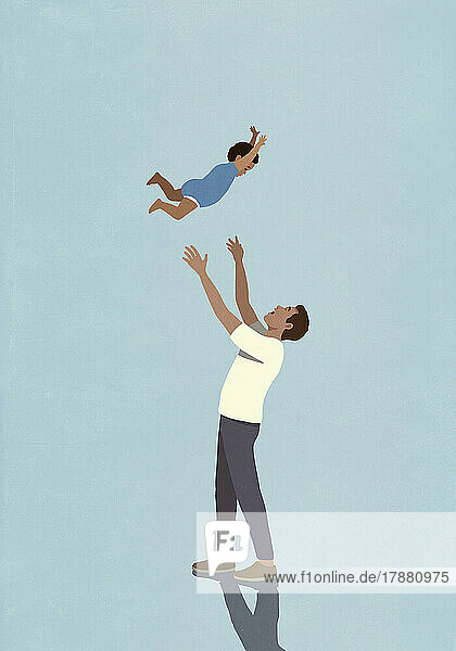 Playful father throwing toddler son overhead on blue background