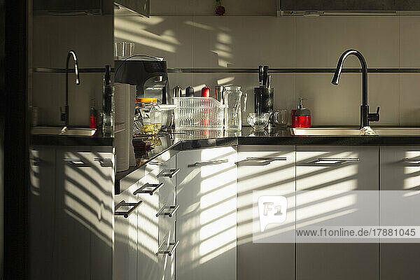 Sunlight and reflections casting shadows in apartment kitchen