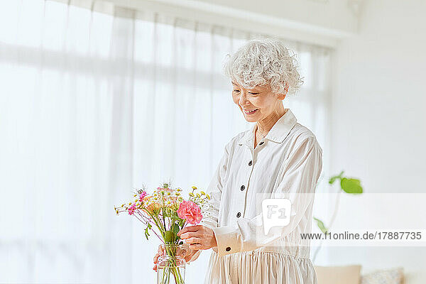 Japanische Seniorin beim Blumenbinden zu Hause