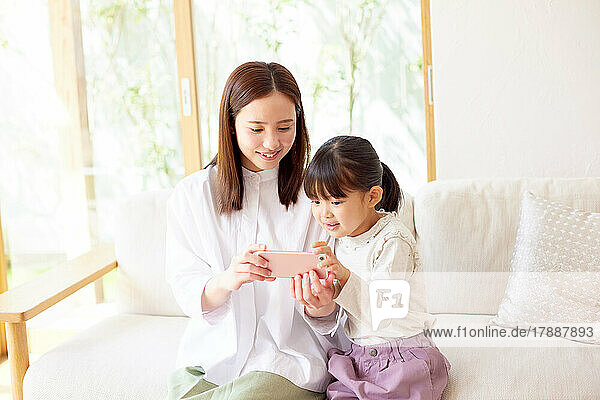 Japanisches Kind und Mutter verwenden Smartphone zu Hause