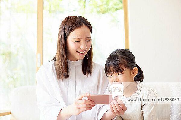 Japanisches Kind und Mutter verwenden Smartphone zu Hause