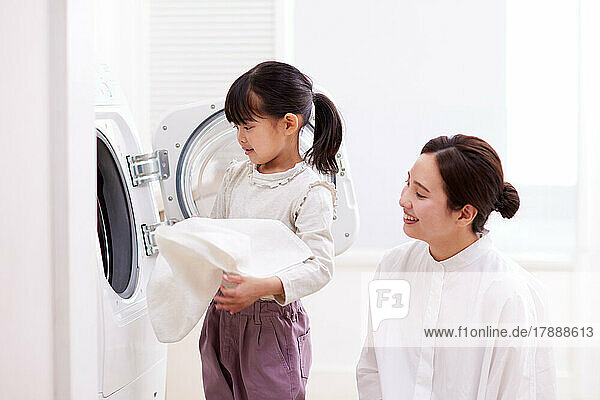 Japanisches Kind und Mutter beim Wäschewaschen zu Hause