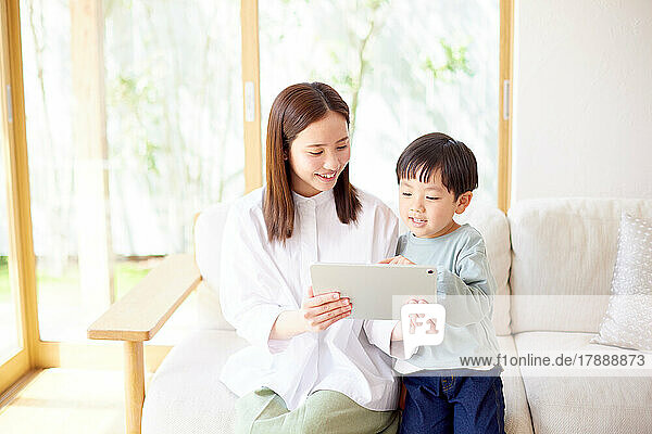 Japanisches Kind und Mutter verwenden Tablet zu Hause
