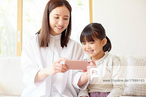 Japanese kid and mother using smartphone at home