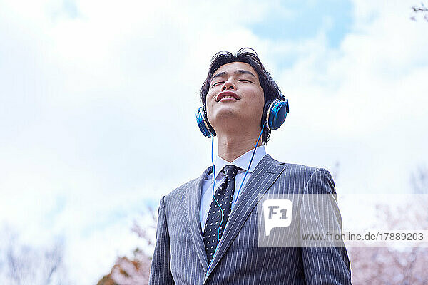Japanese businessman listening to music with headphones