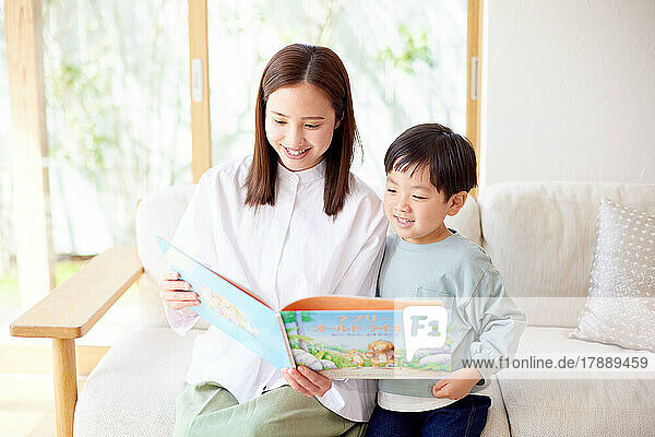 Japanisches Kind und Mutter lesen zu Hause ein Buch
