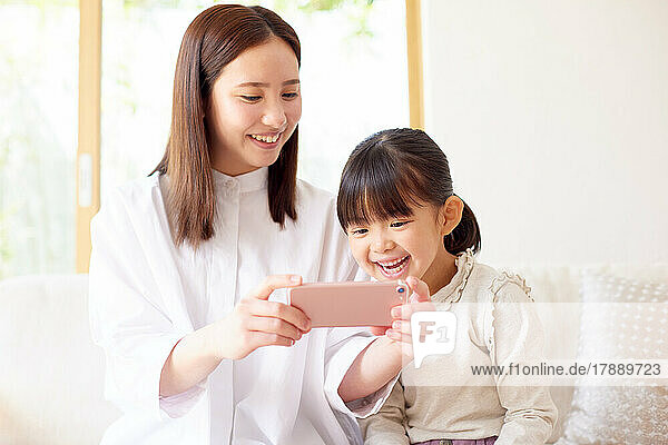 Japanese kid and mother using smartphone at home