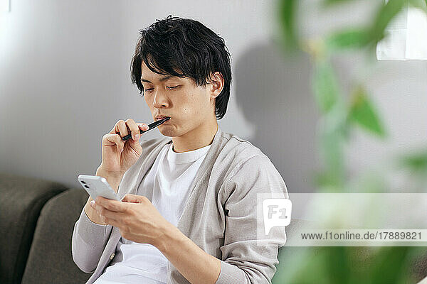 Japanese man brushing teeth on the sofa