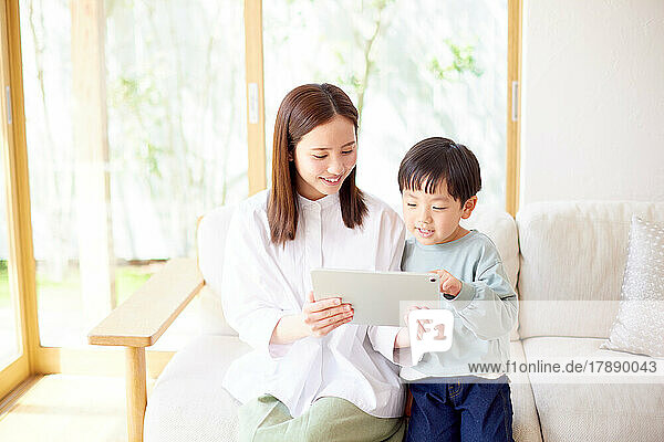 Japanisches Kind und Mutter verwenden Tablet zu Hause