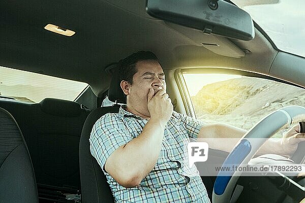 View of a sleepy driver in his car. Tired driver yawning in the car  concept of man yawning while driving. A sleepy driver at the wheel  a tired person while driving