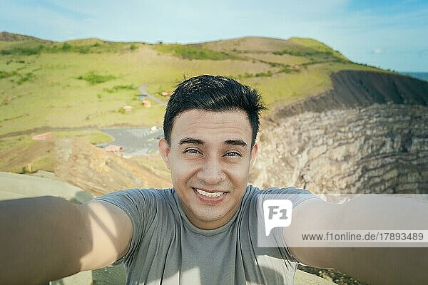 Abenteuerlustiger Mann macht ein Selfie an einem Aussichtspunkt. Nahaufnahme einer Person  die ein abenteuerliches Selfie macht  Tourist  der ein Selfie an einem Aussichtspunkt macht. Gutaussehender Tourist macht ein Selfie im Urlaub. Volcán Masaya  Nicaragua  Mittelamerika