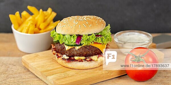 Hamburger cheeseburger fast food meal with fries on wooden board Panorama in Stuttgart  Germany  Europe