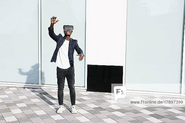 Man with virtual reality simulator gesturing in front of wall