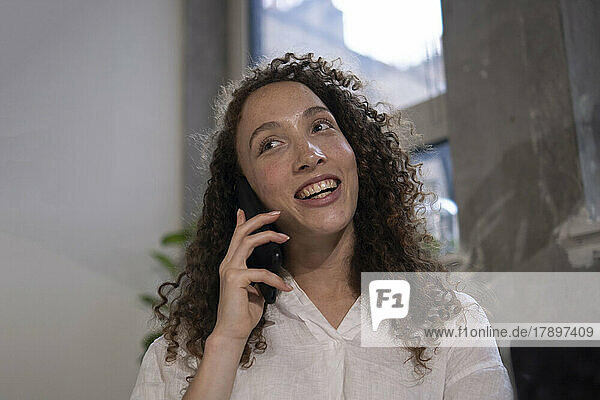 Happy businesswoman talking on mobile phone in office