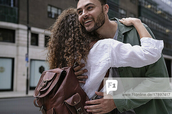 Glücklicher Mann umarmt Frau vor Gebäude