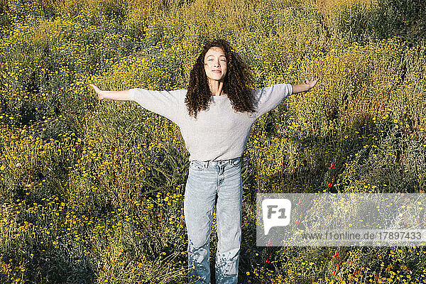 Young woman with arms outstretched standing in field
