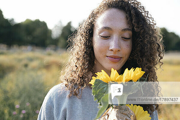 Woman with curly hair looking at sunflower