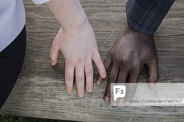 Woman touching boyfriend's finger on wooden bench
