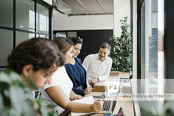 Businesswoman with colleagues working on laptop in modern office