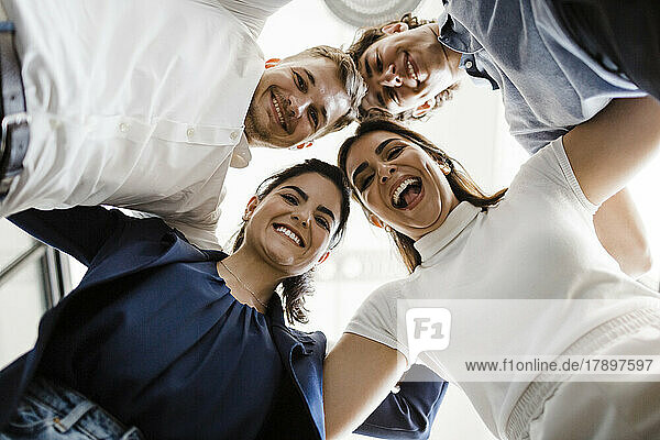 Happy business people huddling together in office