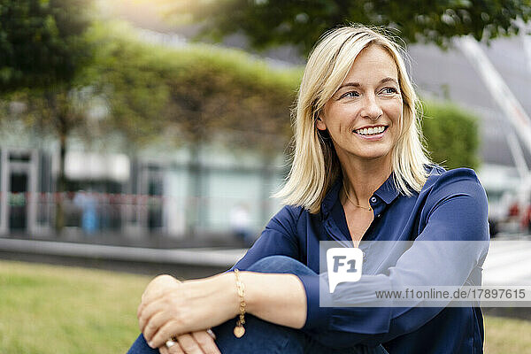Mature smiling businesswoman sitting in park