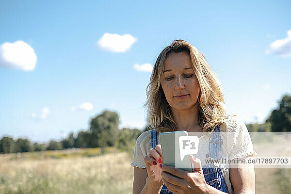 Smiling mature woman using smart phone on sunny day